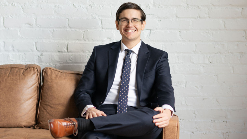 Mark Rivera CPA sitting confidently on a couch, dressed in a suit and tie, smiling, conveying professionalism and approachability for tax preparation and consulting services.